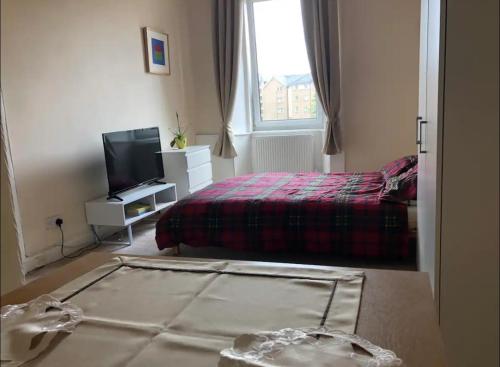 a bedroom with a bed and a tv and a bedskirtspectspectspectspects at Cosy, large double room in a shared flat in Edinburgh