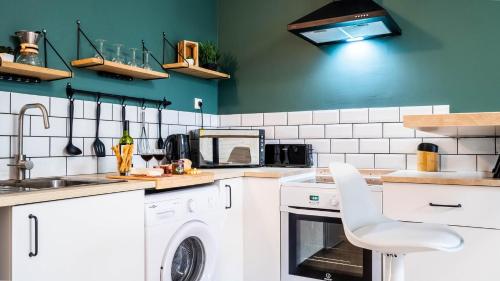 - une cuisine avec des appareils électroménagers blancs et des murs verts dans l'établissement Le Contemporain - Bel appartement T2 à Poitiers, à Poitiers