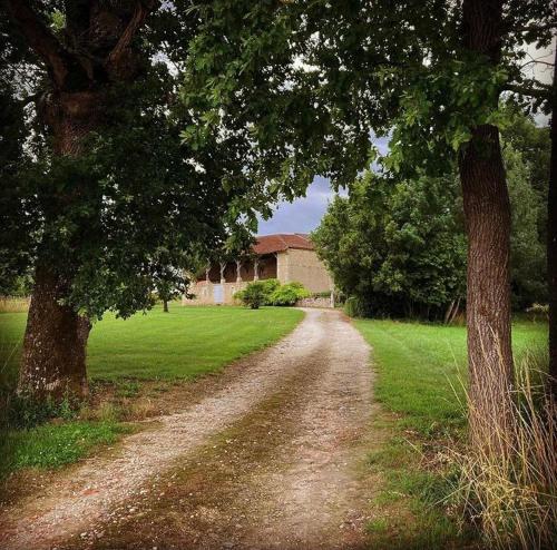 a dirt road with two trees and a house at Le Clos Boissière - Gîte Cosy in Valence-sur-Baïse