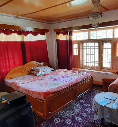a bedroom with a large bed with red curtains at Gurez Retreat in Kanzalwan
