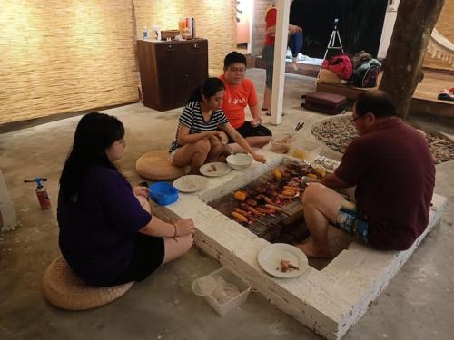 a group of people sitting around a table with food at Wabi Sabi House Broga in Semenyih