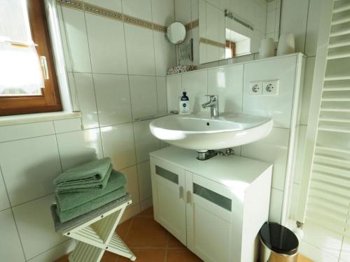 Baño blanco con lavabo y espejo en Ferienwohnung Stuiber, en Haarbach