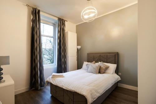 a bedroom with a bed and a window at Lovely, Recently Refurbished Two Bedroom Apartment in Glasgow