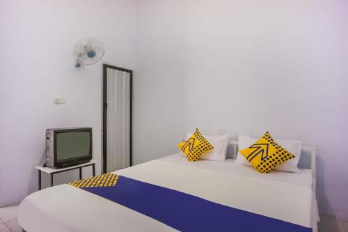 1 dormitorio con 2 camas y TV en OYO 93304 Wisma La Oda Syariah en Pangkajene