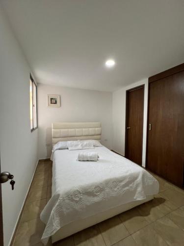 a bedroom with a white bed with a wooden cabinet at Gianina house in Barranquilla