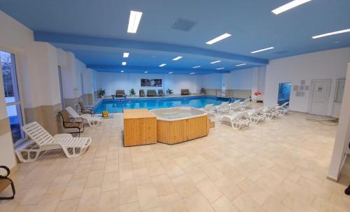 una piscina con sillas y mesas blancas y una piscina en Conacul Domnesc en Suceava