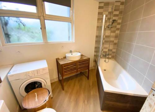 a bathroom with a tub and a sink and a washing machine at Le Général - 4 personnes - Poitiers - La Conciergerie in Poitiers