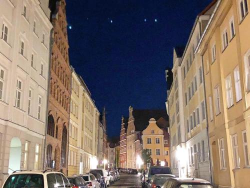 a city street at night with cars parked at Ferienwohnungen in der Altstadt Stralsund in Stralsund