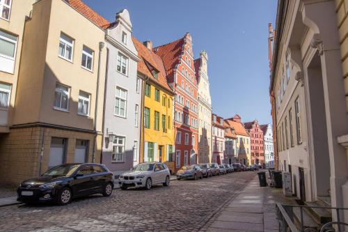 a city street with cars parked on a cobblestone street at Ferienwohnungen in der Altstadt Stralsund in Stralsund
