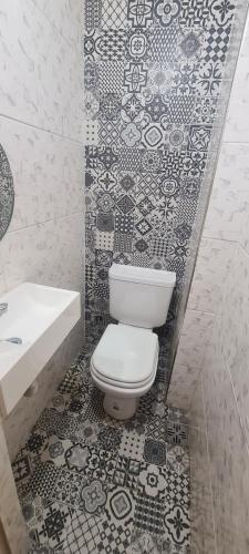 y baño con aseo, lavabo y azulejos. en Departamento 4 ambientes, 3 hab en Buenos Aires