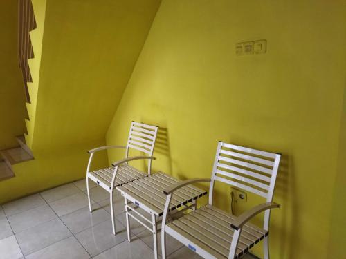 2 chaises et une table devant un mur jaune dans l'établissement OYO 93306 Penginapan Permata Hijau Syariah, à Parepare