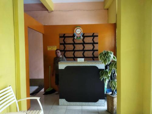 Un homme debout à un comptoir dans une pièce dans l'établissement OYO 93306 Penginapan Permata Hijau Syariah, à Parepare