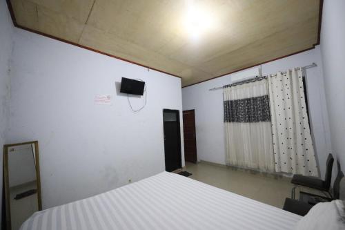 1 dormitorio con 1 cama y TV en la pared en OYO 93306 Kos Citra Syariah, en Parepare