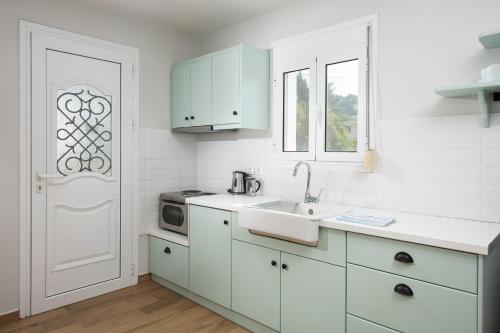 - une cuisine avec des placards blancs, un évier et une porte dans l'établissement Barefoot Contessa, à Lourdhata