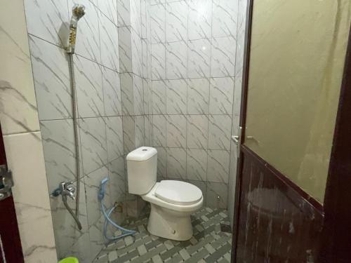 y baño con aseo en una pared de azulejos. en OYO 93306 Kos Citra Syariah, en Parepare