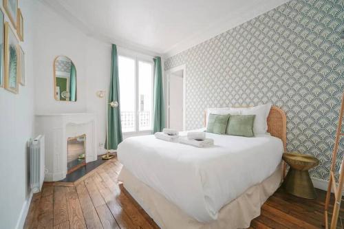 ein Schlafzimmer mit einem großen weißen Bett und einem Kamin in der Unterkunft Apartment proche Vaugirard - Sauge - III in Paris
