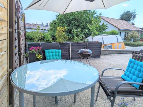 a glass table and chairs on a patio with an umbrella at W3 - Urlaubsmagie - Maisonette-Wohnung mit Pool in Lichtenhain