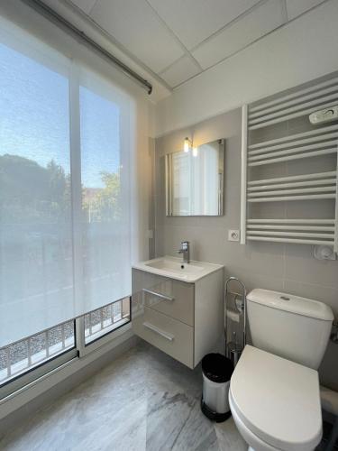 une salle de bain avec toilettes, lavabo et fenêtre dans l'établissement Esperance, à Cannes