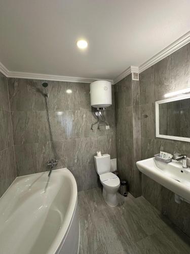 a bathroom with a tub and a toilet and a sink at Garden Hall in Ternopilʼ