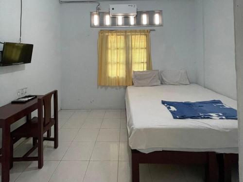 1 dormitorio con cama, escritorio y ventana en OYO 93178 Al Bait Homestay. en Lhokseumawe