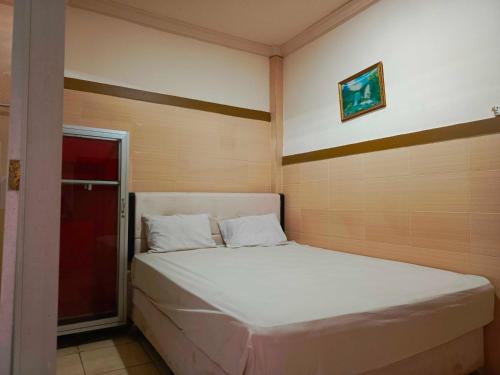um quarto com uma cama branca num quarto em OYO 93278 Wisma Syariah Lahundape em Kendari