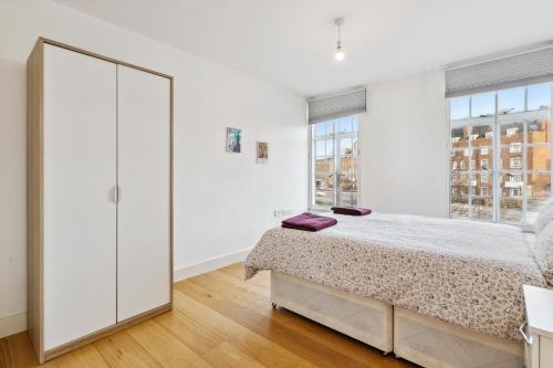 Dormitorio blanco con cama y ventana grande en Cozy Central London Residence Stockwell, en Londres