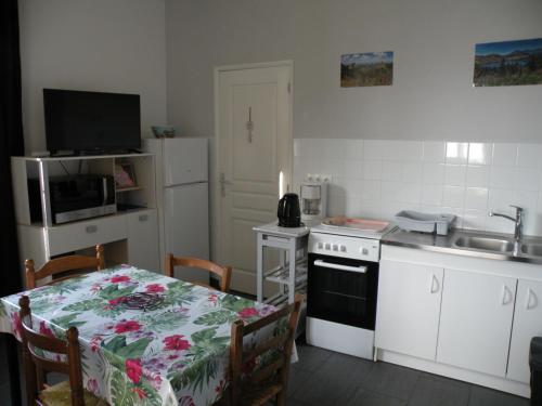 une petite cuisine avec une table, une cuisinière et un évier dans l'établissement Rose, 4 pers. Villa Saint Antoine, Orcival, Sancy, à Orcival