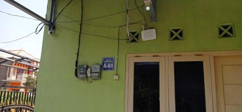 um edifício verde com dois telemóveis ao lado em SPOT ON 93210 Griya Kos Kanjeng Mami Syariah em Jombang