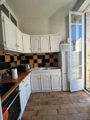 a kitchen with white cabinets and a refrigerator at Grand studio lumineux en plein coeur de Versailles in Versailles