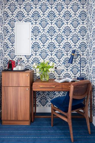 a desk with a chair in a room with blue and white wallpaper at Hotel Le Place d'Armes - Relais & Châteaux in Luxembourg