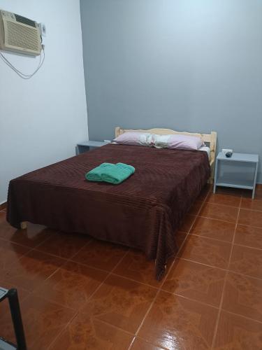 a bed with a brown blanket and two towels on it at Hostel el Amanecer in Puerto Iguazú