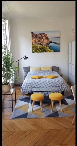1 dormitorio con 1 cama y 2 taburetes amarillos en Grand studio lumineux en plein coeur de Versailles, en Versalles
