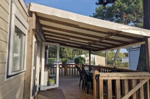 awning over a deck with a table and chairs at MOBIL-HOME 3 CHAMBRES LA TESTE DE BUCH in La Teste-de-Buch