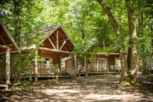 a log cabin in the woods with a porch at Huttopia Versailles in Versailles