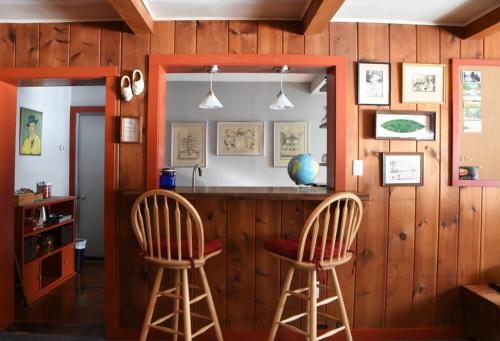 dwa stołki barowe w kuchni z drewnianymi ścianami w obiekcie Panther Mountain Lodge w mieście Phoenicia