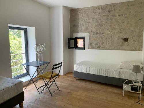 une chambre avec un lit, une table et une fenêtre dans l'établissement Le Moulin de Mirande, à La Tour-sur-Orb