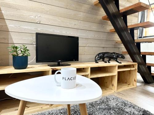 a room with a tv and a table with a coffee cup at LA CITADINE - Parking - Calme in Mont-de-Marsan