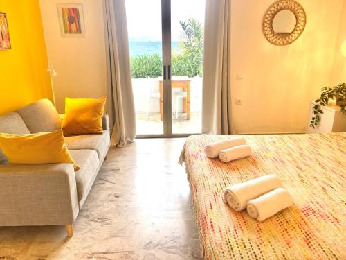 a bedroom with a bed and a couch and a window at The Beachhouse Apartments in Vaia