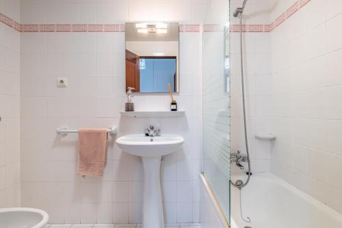 a white bathroom with a sink and a shower at Sea View in Câmara de Lobos