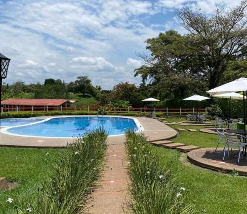 uma piscina num quintal com mesas e guarda-sóis em Finca Hotel Sol Y Luna em Calarcá