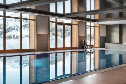 a swimming pool in a building with windows at Résidence Manaka in Aime La Plagne