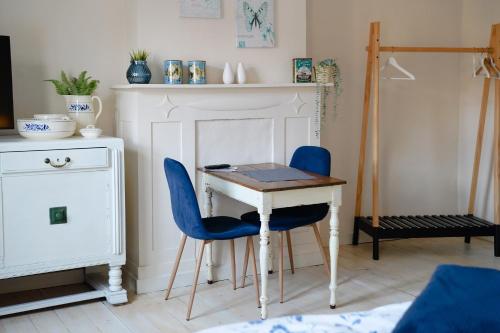 een kamer met een tafel en twee blauwe stoelen bij Gastenkamers In de Bleick in Rekem
