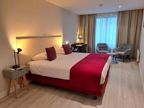 una camera d'albergo con un grande letto con una coperta rossa di Hotel Acacia a Bruges