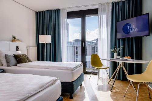 a hotel room with two beds and a table at THE FLAG München M. in Munich