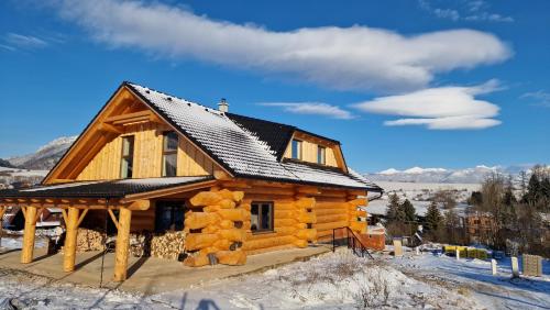 a log cabin with a black roof in the snow at Zrub Poľana - Liptovská Mara in Ižipovce