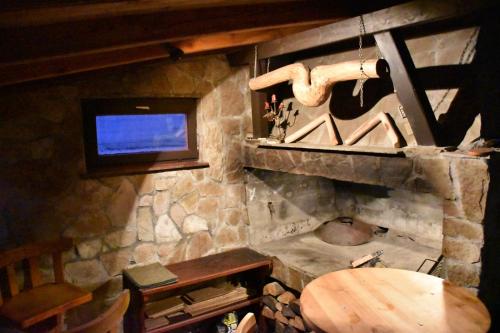 Villa Šola في كوبريس: غرفة بها موقد حجري مع تلفزيون وطاولة خشبية