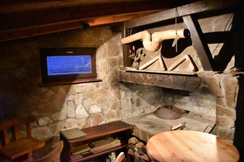 a room with a stone fireplace with a television and a wooden table at Villa Šola in Kupres