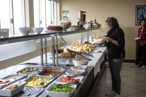 a woman standing in front of a buffet of food at Hotel do Reinildo II in Cachoeira Paulista