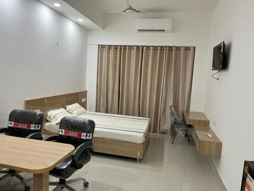 Habitación con cama, mesa y sillas. en Gaur City Centre en Ghaziabad