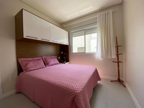 ein Schlafzimmer mit einem rosa Bett und einem Fenster in der Unterkunft Miss Sarajevo Praia Palmas Governador Celso Ramos in Governador Celso Ramos